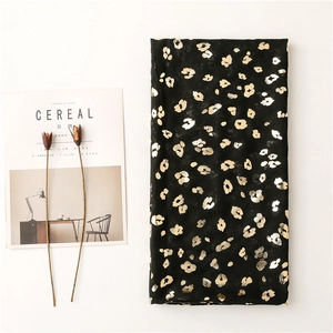 Detailed view of black scarf featuring metallic gold leopard print on lightweight fabric