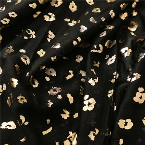 Close-up of black leopard print scarf with golden foil texture and soft fabric drapes