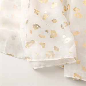 Close-up of lightweight beige scarf featuring gold foil leopard print and rolled edges
