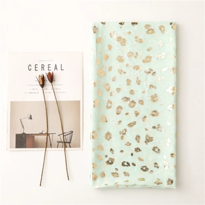 Detail of mint green scarf with gold leopard print foil next to a Cereal magazine