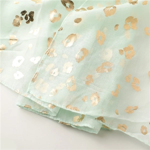 Detail of mint green scarf featuring metallic gold leopard print on lightweight fabric