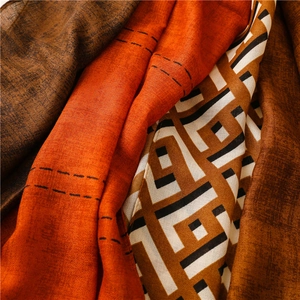 Detail of multi-color woven scarf with orange and beige geometric patterns and fringe edges