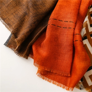 Detail of color-block scarf featuring orange and brown tones with frayed edges