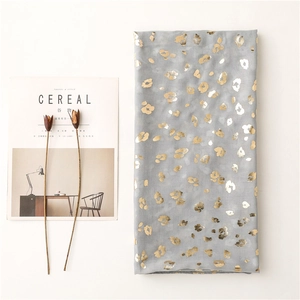 Macro detail of grey scarf featuring gold foil leopard print next to decorative props