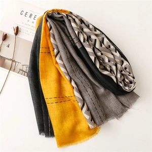 Detail of color-block scarf with ginger yellow, grey patterns and frayed fringe edges