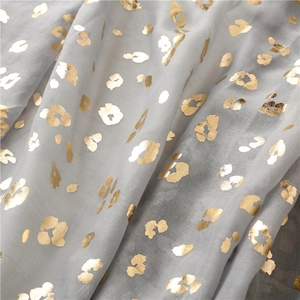 Macro view of grey scarf showing metallic gold leopard print on lightweight fabric