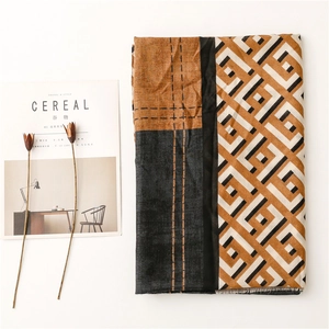 Detail of soft geometric patterned scarf with orange, black and beige color blocking