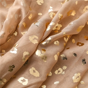 Macro view of gold foil leopard print on light beige sheer fabric shawl wrap