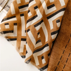 Close-up of geometric woven scarf showing soft texture and frayed edge details