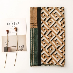 Detail of color-block scarf with geometric patterns and fringe edges on white background