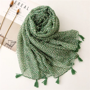 Dark green floral scarf with yellow flowers and long fringe displayed on a magazine