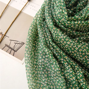 Detail of green floral scarf with white daisies and yellow accents on lightweight fabric