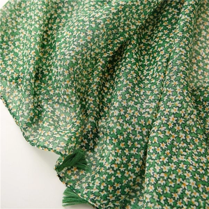 Close-up of green daisy print scarf with delicate fringe tassels and soft linen texture