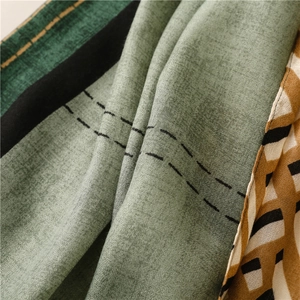 Detailed close-up of textured olive green cotton linen scarf with geometric color block stitching