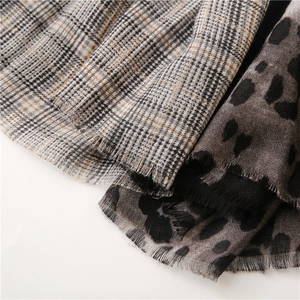 Close-up of leopard print and plaid scarf texture with soft fringe tassel edges