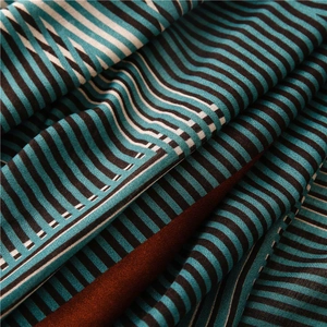 Détail du tissu à rayures géométriques bleu et beige offrant un drapé élégant et soyeux