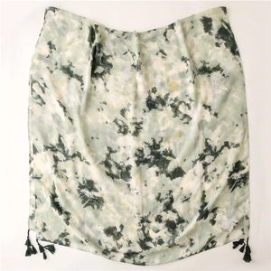 Detail of lightweight green tie-dye scarf featuring soft texture and green tassels