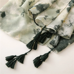 Detailed close-up of ink painting scarf texture with elegant dark green tassels