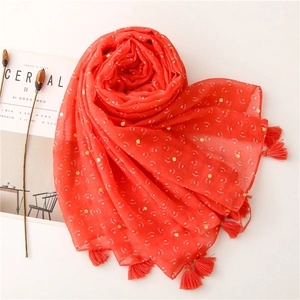 Detailed macro view of red cotton linen scarf with gold foil dots and tassel fringe