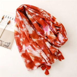 Close-up of tie-dye cotton linen scarf featuring orange tassels and artistic ink pattern