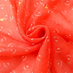 Macro view of coral orange cotton linen scarf with white paw prints and gold foil details