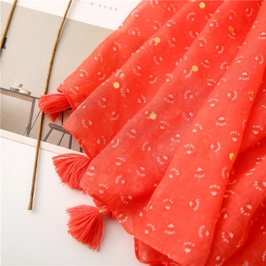 Detail of red cotton scarf featuring gold foil polka dots and elegant fringe tassels