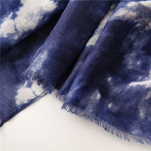 Dettaglio di sciarpa in cotone tie-dye blu e bianco con frange fatte a mano
