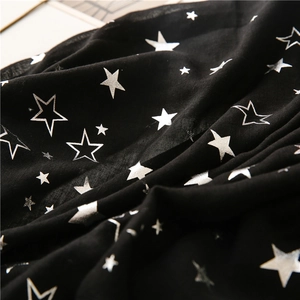 Detail shot of black cotton scarf fabric featuring silver star patterns and soft texture