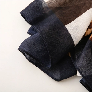 Gros plan détaillé sur le motif léopard et la texture tissée de l'écharpe en coton bleu