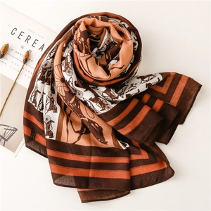 Detail of vintage carriage and chain print on elegant silk-touch scarf with orange border