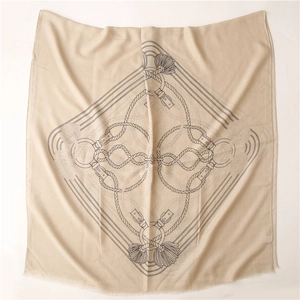 Dettaglio di sciarpa beige in cotone e lino con stampe di cinture e frange classiche