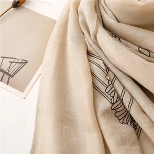 Dettaglio sciarpa in cotone e lino beige con elegante motivo a linee nere e tessuto morbido