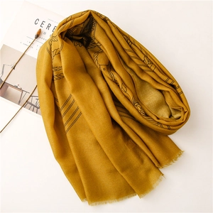 Dettaglio della sciarpa in cotone lino giallo con motivi geometrici e frange morbide
