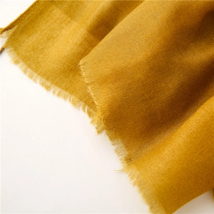 Dettaglio macro della sciarpa in cotone e lino giallo zenzero con bordi sfrangiati