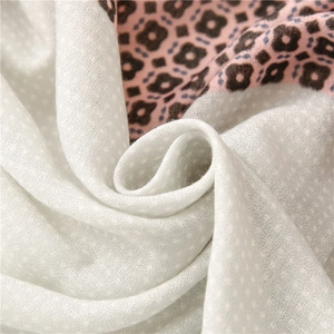 Dettaglio del tessuto leggero della sciarpa con pois e patchwork floreale geometrico