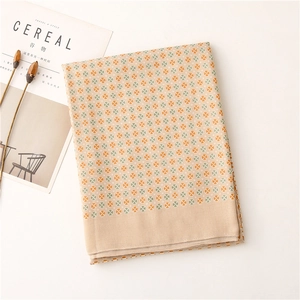 Dettaglio di sciarpa beige a quadretti con fiori arancioni e verdi su rivista Cereal