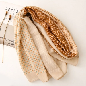 Dettaglio della sciarpa leggera beige con motivi floreali geometrici e cuciture rifinite