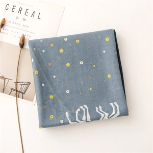 Flat lay detail of hazy blue scarf with yellow floral patterns and art silhouette
