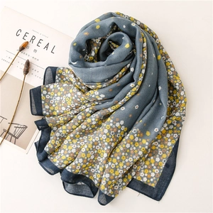 Detail of grey-blue floral scarf with yellow flowers and navy blue border trim
