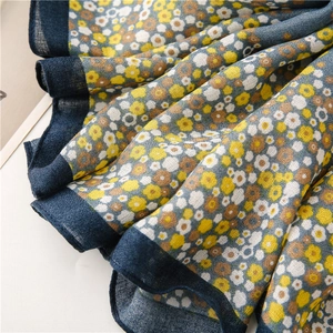 Macro shot of cotton linen scarf with daisy print and elegant dark blue edge detailing