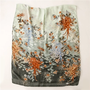 Détail d'un châle floral vert foncé avec impression dégradée menthe et gris