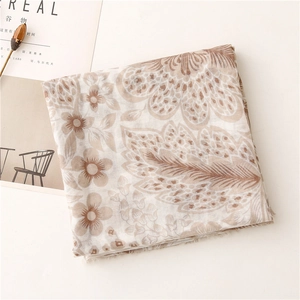 Flat lay of folded floral voile scarf with vintage beige flower and feather patterns