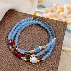 Detailed close-up of multi-layer beaded bracelet with light blue and red accents