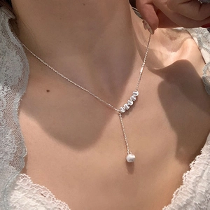 Gros plan détaillé d'un collier de clavicule argenté avec cinq perles brossées et un pendentif