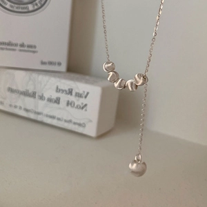 Gros plan du collier en Y argenté avec perles en métal dépoli sur une boîte blanche