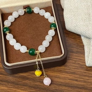 Détail du bracelet de perles avec pierres vertes et touches dorées dans un écrin chic
