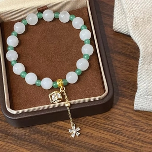 Bracelet en perles vertes et blanches avec breloque cube en or dans son coffret