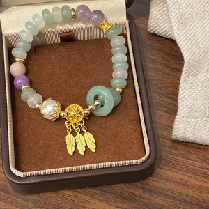 Bracelet en pierres naturelles vertes de style ethnique avec breloques plumes dorées en boîte