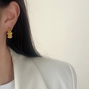 Elegant gold flower cluster earrings with zirconia on a model wearing white