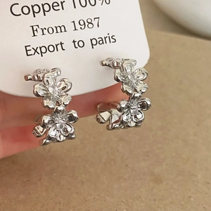 Close-up of double-layer flower hoop earrings made of copper with cubic zirconia accents